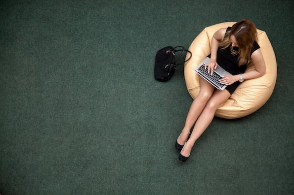 woman sitting in a beanbag chair using a laptop to research best WordPress themes for business websites 