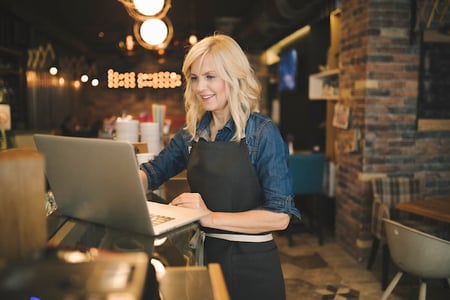 person viewing vintage website designs on a laptop in a restaurant
