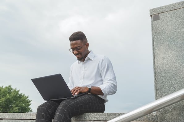 Man sitting outside using a laptop to monetize a wordpress blog website