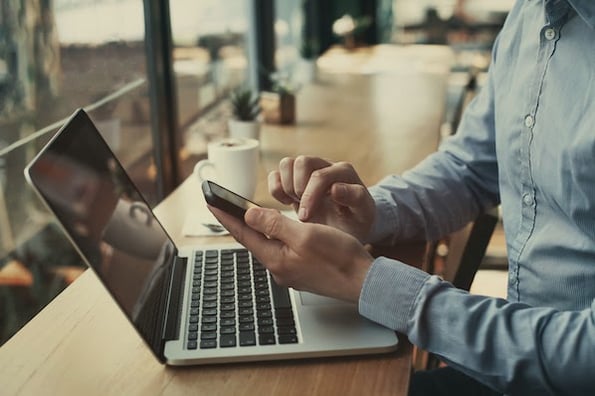 person using a mobile device and a laptop computer to design and test a site search bar