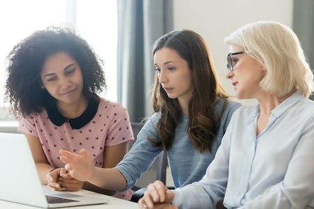 Three women using a laptop to leverage browser caching on a wordpress website