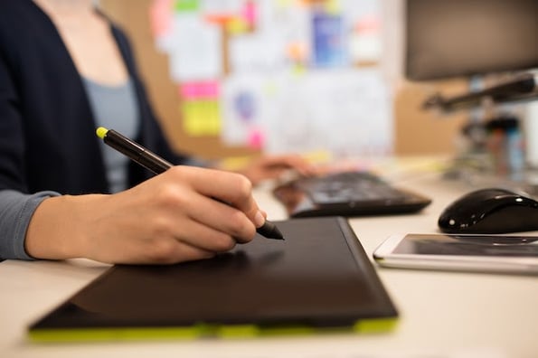 person creating an SVG file with a computer and drawing pad