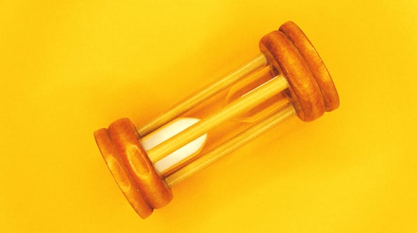 Orange, wood hourglass on yellow background