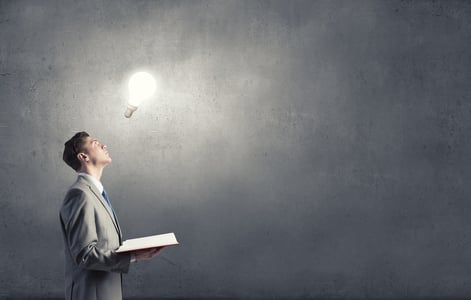 Businessman holding opened book with glass glowing light bulb.jpeg