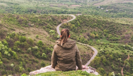 Woman atop a rock looking at the journey ahead