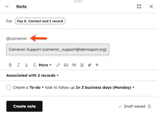 The note editor is displayed on a contact record. An arrow points to the @name of the contact indicating this will mention the user.