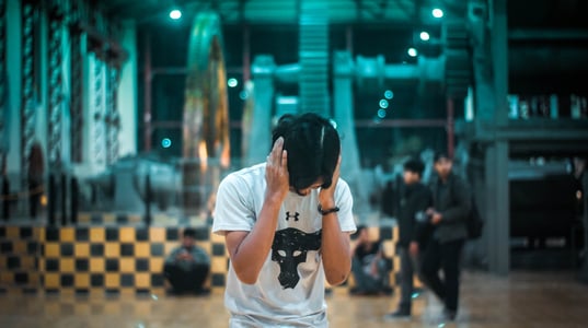 Person hunched over covering ears in industrial building