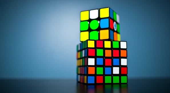Two Rubik's cubes stacked in front of a blue background
