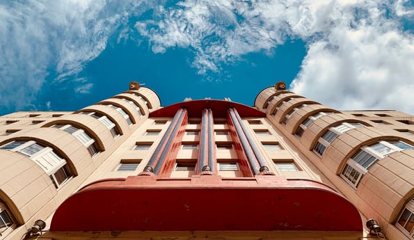 Streamlined, futuristic orange building reaching up to a bright blue sky