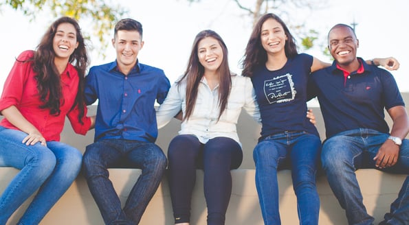 Three smiling women and two smiling men seated together in solidarity.