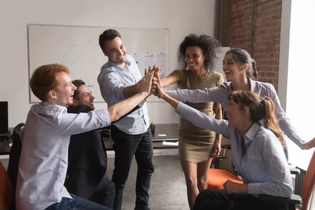 sales reps high-fiving in a sales huddle