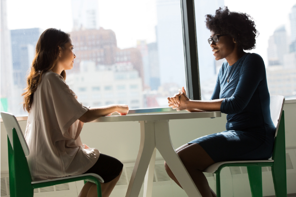 deux femmes assises à un bureau discutent 