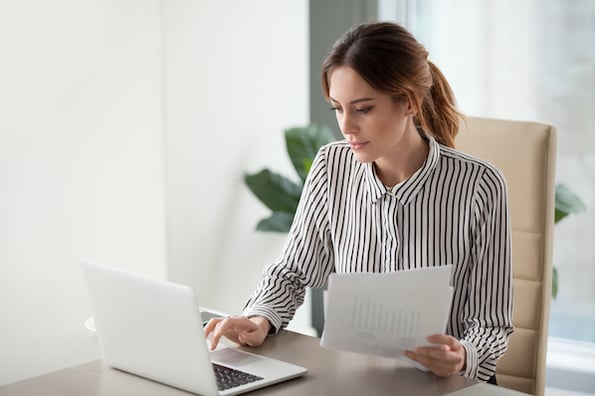 Learning how to make a professional website, a woman looks from her notes to her screen.