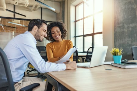 Two people in an office look at a laptop and discussing API economy