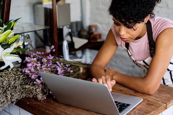 Businesswoman in a flower shop using a computer to find a one page WordPress theme for her website