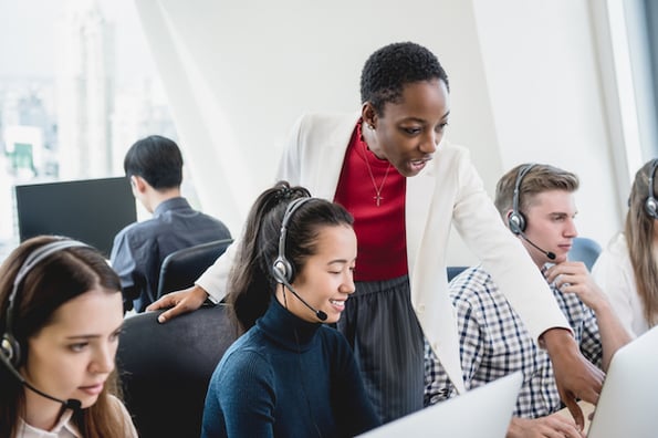 Call center manager speaking with a team member, who's talking on the phone using call center software