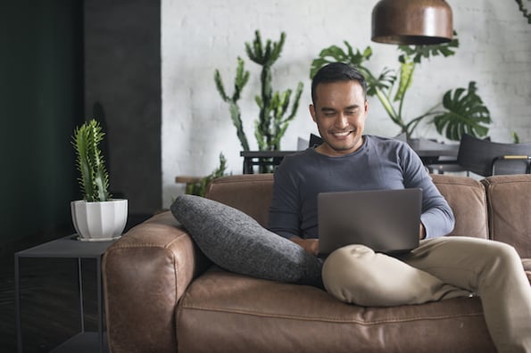 man sitting on a couch using a laptop computer to install a Call To Action WordPress plugin on his website