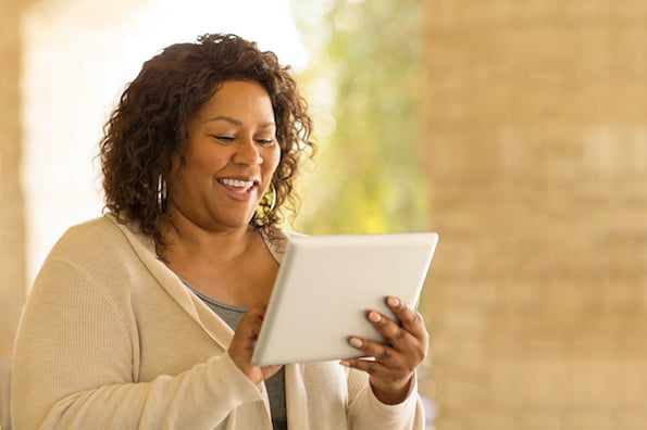 woman using a tablet to browse for digital downloads wordpress themes