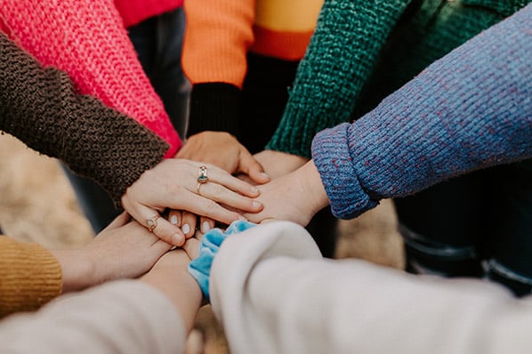 Gruppe von Menschen legen Hände übereinander symbolisierend für Empathie