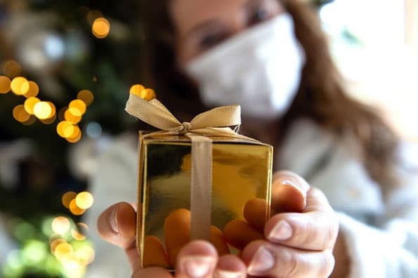 A person gives a gift they bought while holiday shopping online during the COVID-19 pandemic.