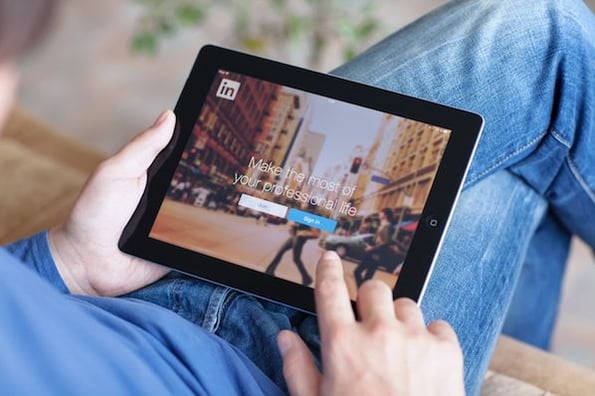 Professional wonders how to write a LinkedIn recommendation as they network on a tablet.