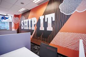 Mural laranja que diz “ship it” em uma parede no escritório da HubSpot em Singapura