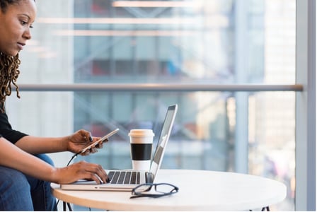 Collaboratrice sur son téléphone devant un ordinateur