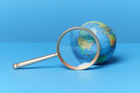 O que é a estratégia do Oceano Azul? - Imagem mostra um globo terrestre posicionado em frente a uma lupa - idéia transmitida pela imagem é a de visualizar soluções focando em áreas não exploradas pela concorrência 