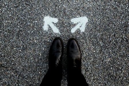 paire de chaussures noire devant deux flèches en directions opposées