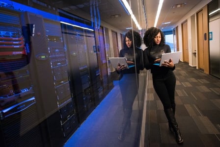 femme avec un ordinateur dans une salle de serveurs