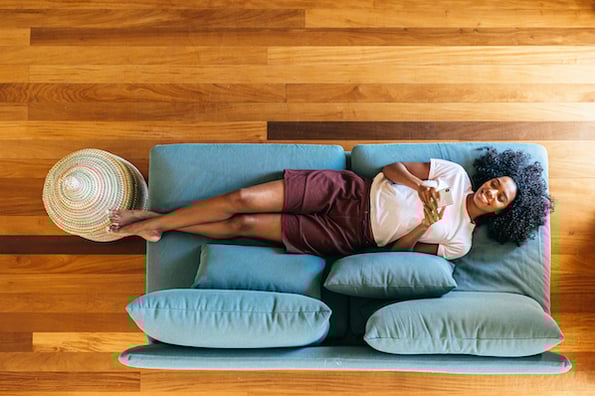 woman lying on a blue couch using a smartphone to browse a mobile friendly wordpress website