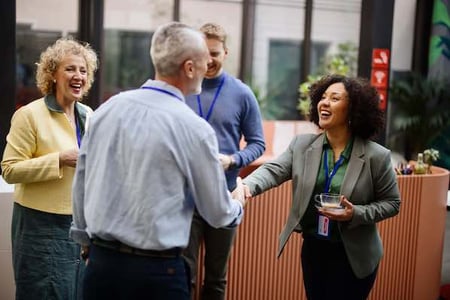 woman practicing networking skills at an event and shaking someones hand