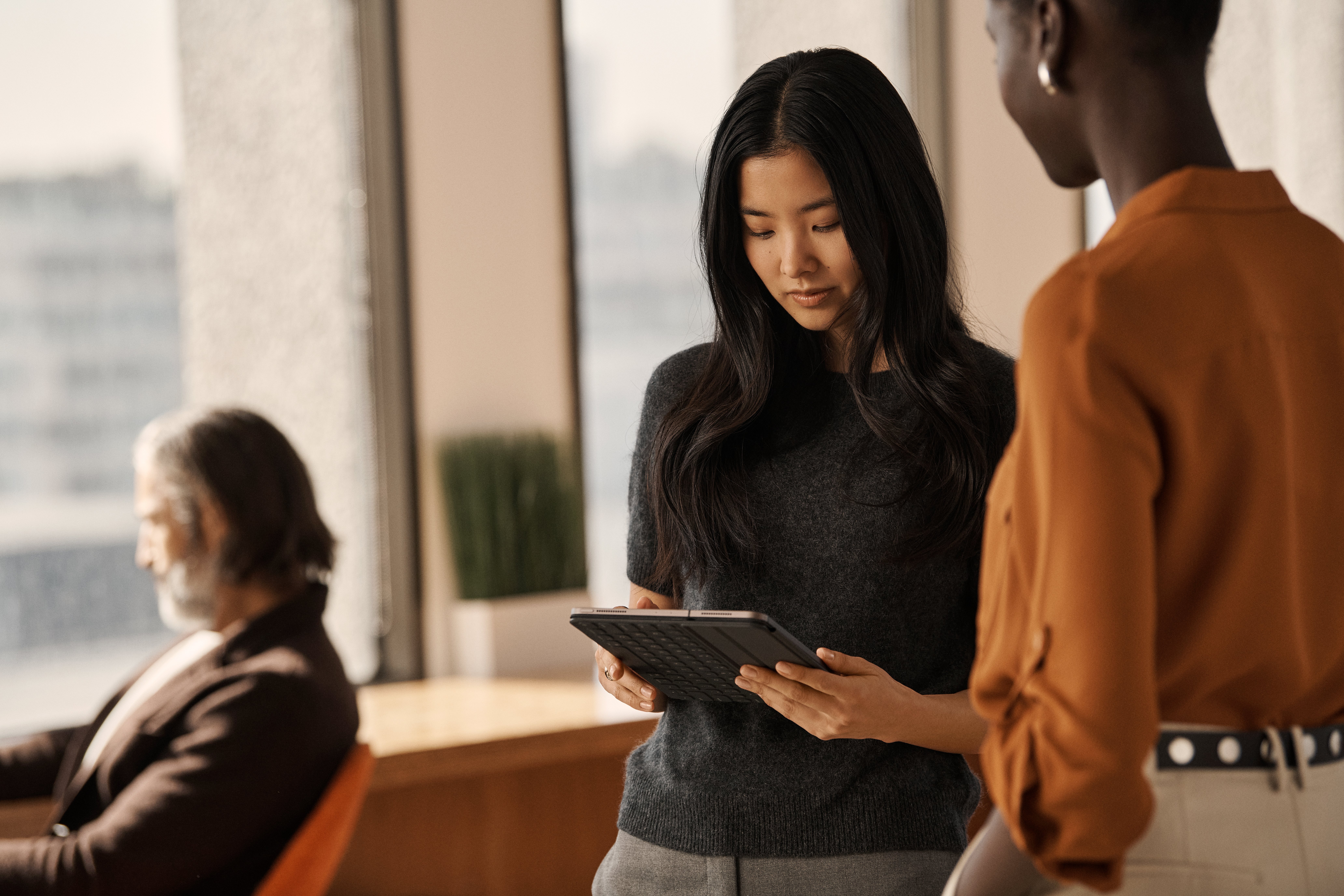 Two women with ipad  man in background