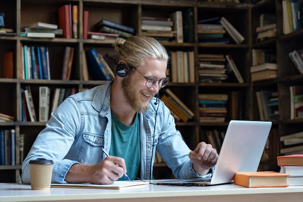 Customer service representative at his laptop with a headset using positive scripting to communicate a solution to a customer's issue