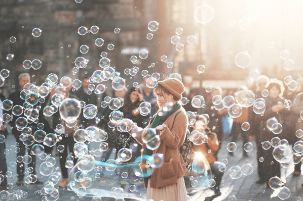 Eine Frau bläst Seifenblasen um Crowdfunding Plattformen zu symbolisieren