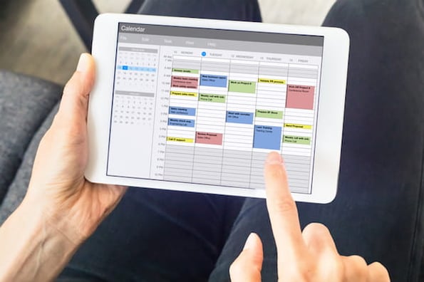marketer using a social media content calendar tool on a tablet
