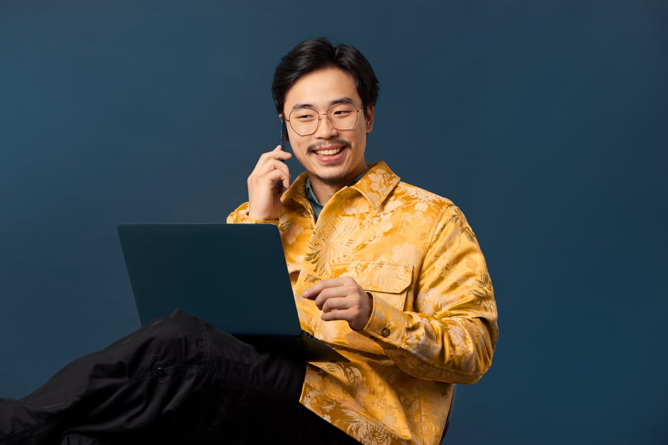 Man with laptop on his knee talking on phone