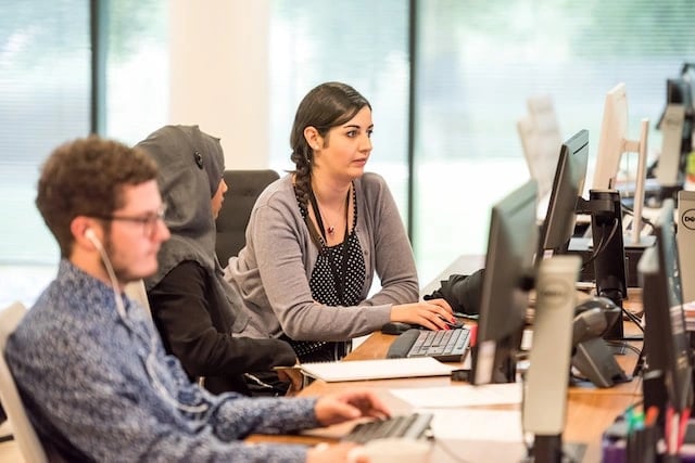 three people sitting beside each other conducting user testing on desktop computers