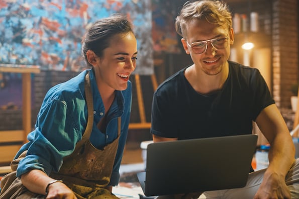 Two artists looking for a WordPress theme for artists on a laptop