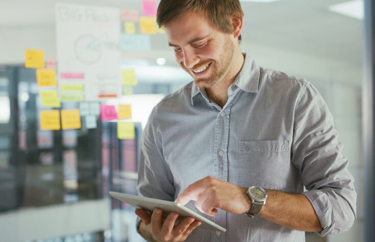 Mann plant B2B-Content-Marketing-Kampagne auf Tablet
