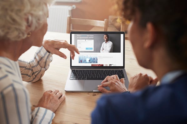 Mitarbeitende unterhalten sich vor Laptop über Regeln und Tipps für gutes Webdesign