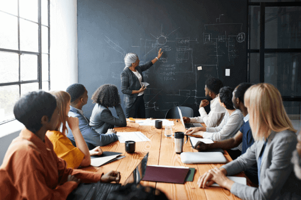 Managerin erklärt Team an Tafel, wie die Optimierung von Landingpages funktioniert