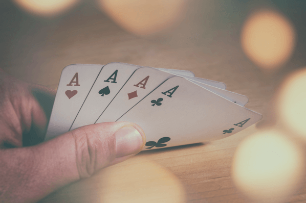 Person hält 4 Asse in der Hand symbolisierend für Verkaufsstrategien