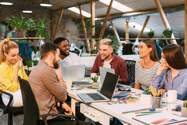 Team sitzt an Tisch und entwickelt Werbeplan