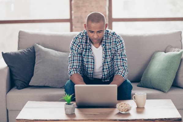 man sitting on a couch using a laptop computer to use the CSS display property