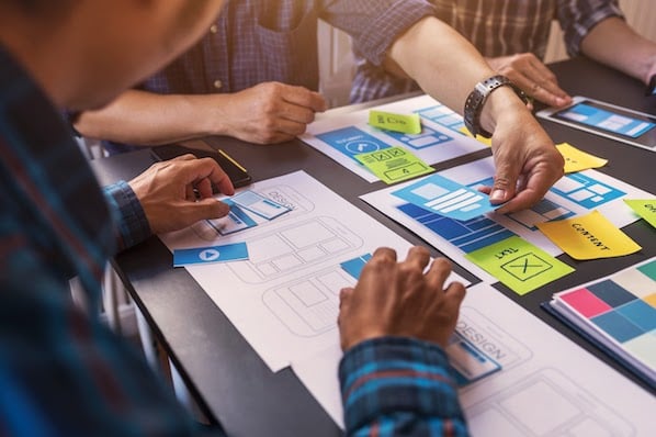 two people prototyping a broken grid layout web design with post-it notes on a table