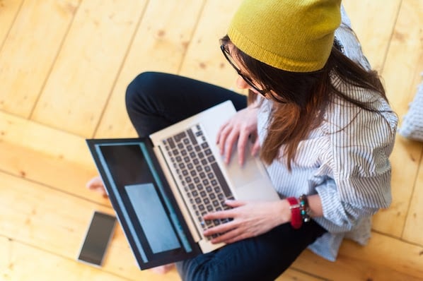 person sitting on the ground using a laptop to add an iframe HTML element to a web page