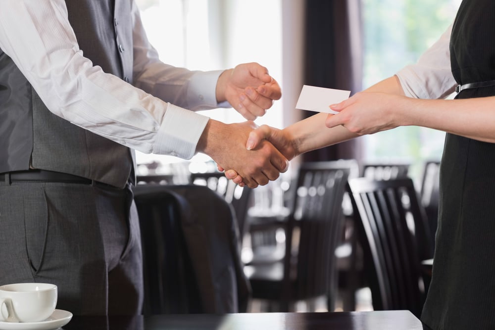 Business people shaking hands after meeting and changing cards in restaurant-1