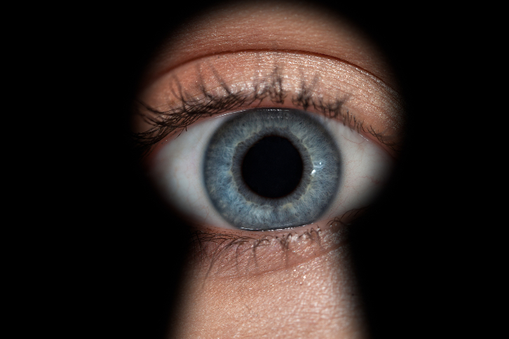 pessoa olhando pela fresta da fechadura de uma porta - referência ao Big Brother Brasil e dar uma 