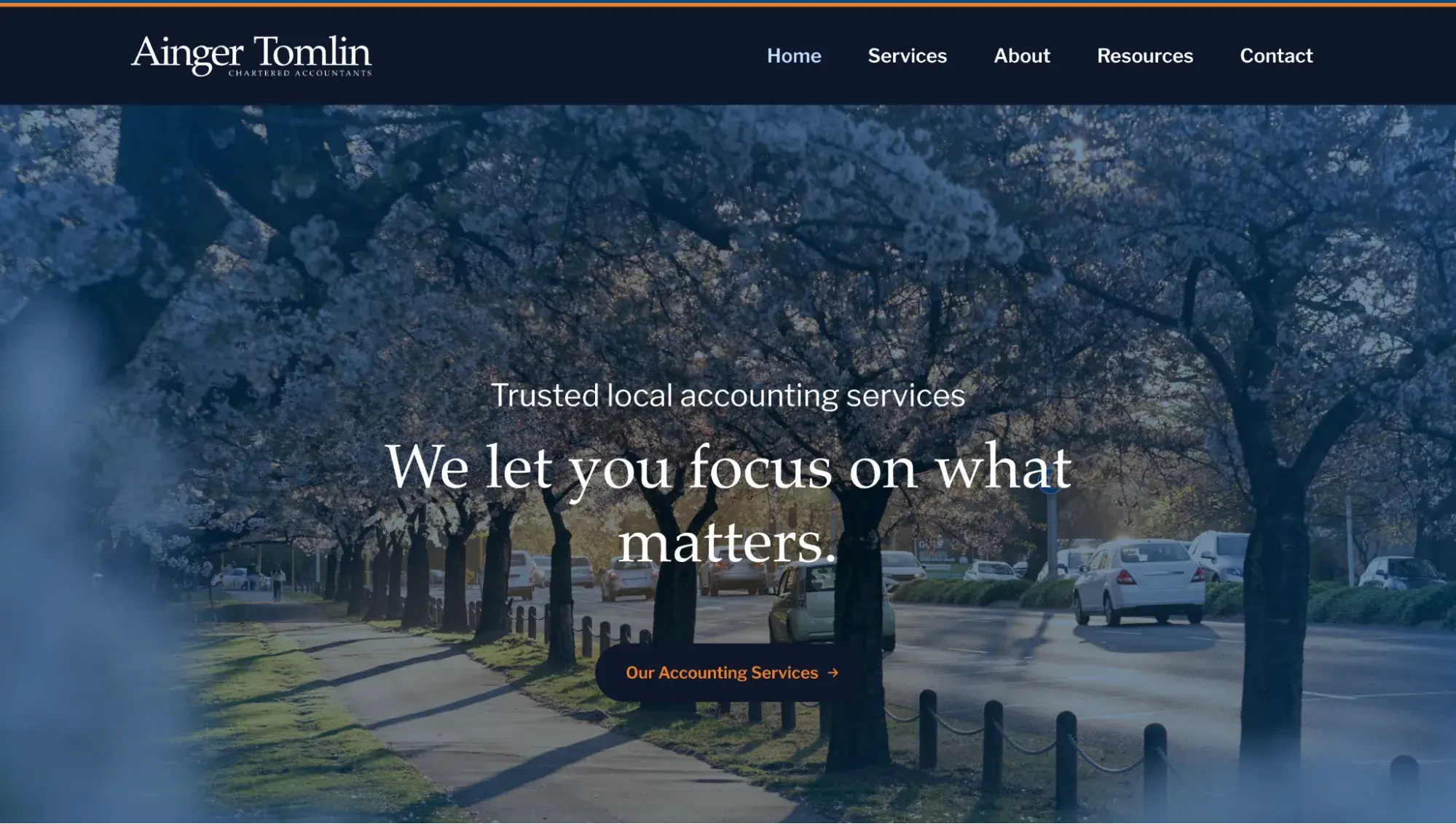 simple website examples from ainger tomlin accounting firm with blue hero image of tree-lined street and white serif headline